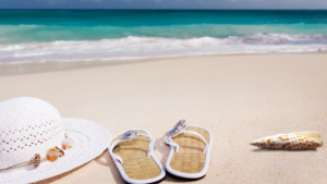 a serene beach scene with a white sun hat, white flip-flops, and a seashell on the sand, with the ocean and waves in the background